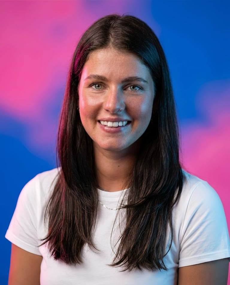 Smiling woman with long dark hair wearing a white t-shirt against a colorful pink and blue gradient background